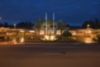 Nighttime exterior view of a senior living facility with warm lighting illuminating the building and surrounding landscaping.