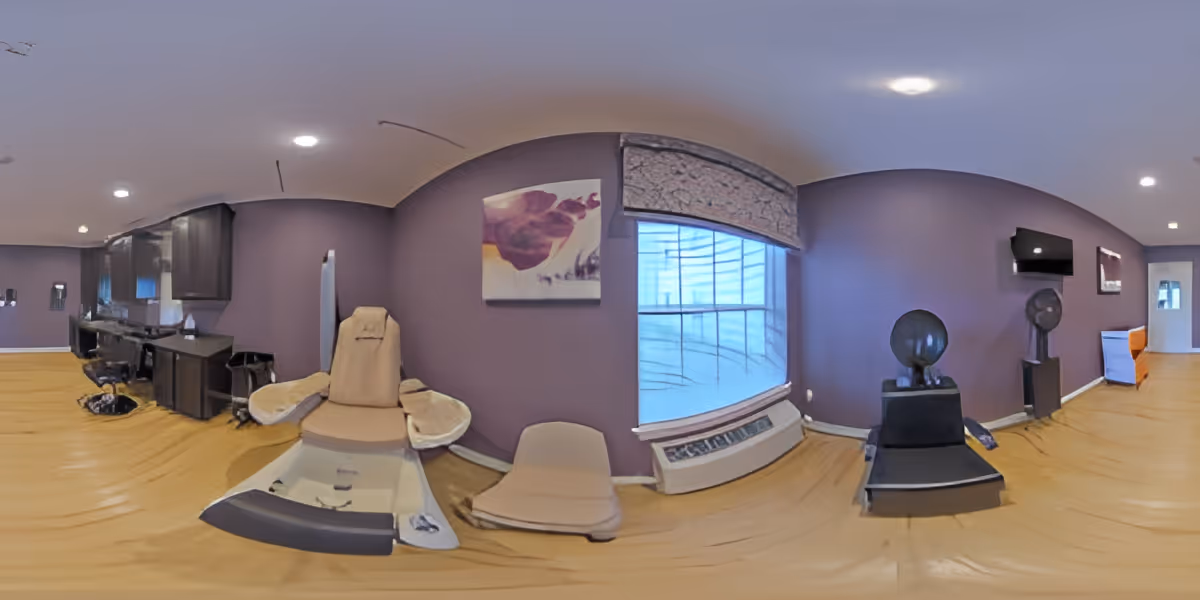 Interior room with purple walls and wood floors featuring pedicure chairs, salon stations, a large window and hair-drying chairs.