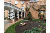 Entrance of a brick senior living facility with a covered porte-cochere, holiday garlands and a landscaped planting bed.
