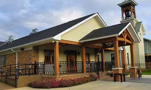 Exterior view of a senior living facility with covered entrance and bell tower