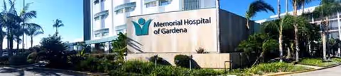 Exterior of Memorial Hospital of Gardena with sign and palm trees.