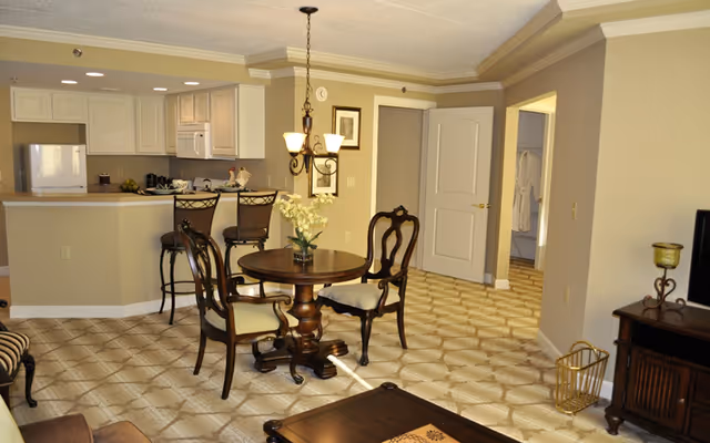 Open-plan living and dining area with a round wooden table and chairs beside a breakfast bar and kitchen.