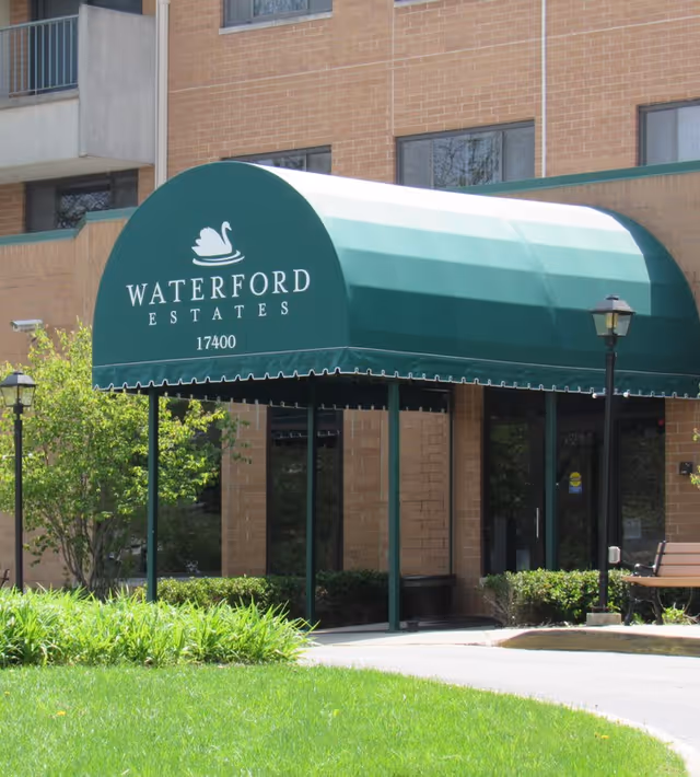 Green entrance awning reading "Waterford Estates" with a swan logo in front of a brick building.