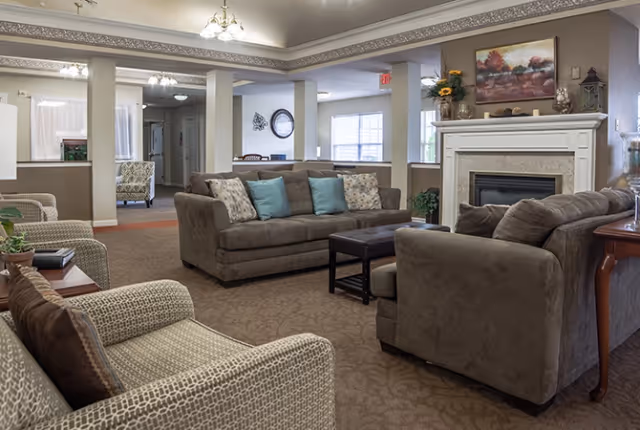 Comfortable living room with sofas, armchairs, a fireplace and decorative accents in a senior living facility.