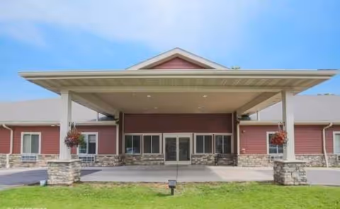 Front entrance of a red senior living building with a covered porte-cochère.