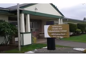 Front entrance of Americana Health & Rehab Center showing a covered porch and a freestanding sign on the lawn.