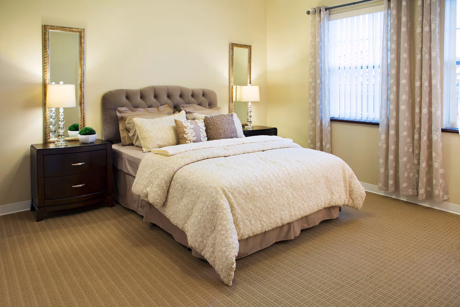 Bright, neatly staged bedroom with a tufted bed, bedside tables and lamps, and a curtained window.