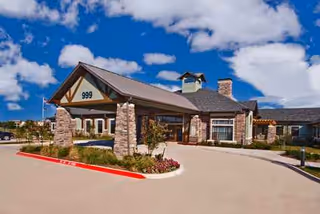 Senior living facility exterior with stone entry and covered driveway.