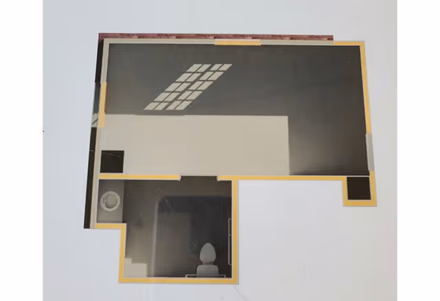 Top-down view of a simple floor plan showing a main room with a window, and a small bathroom area with a toilet and sink.