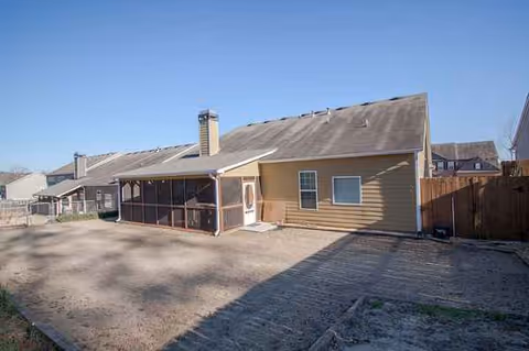 Exterior of a single-story home with a screened porch and bare dirt yard