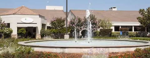 Front view of Regents Point senior living facility with a circular fountain and landscaped entrance.