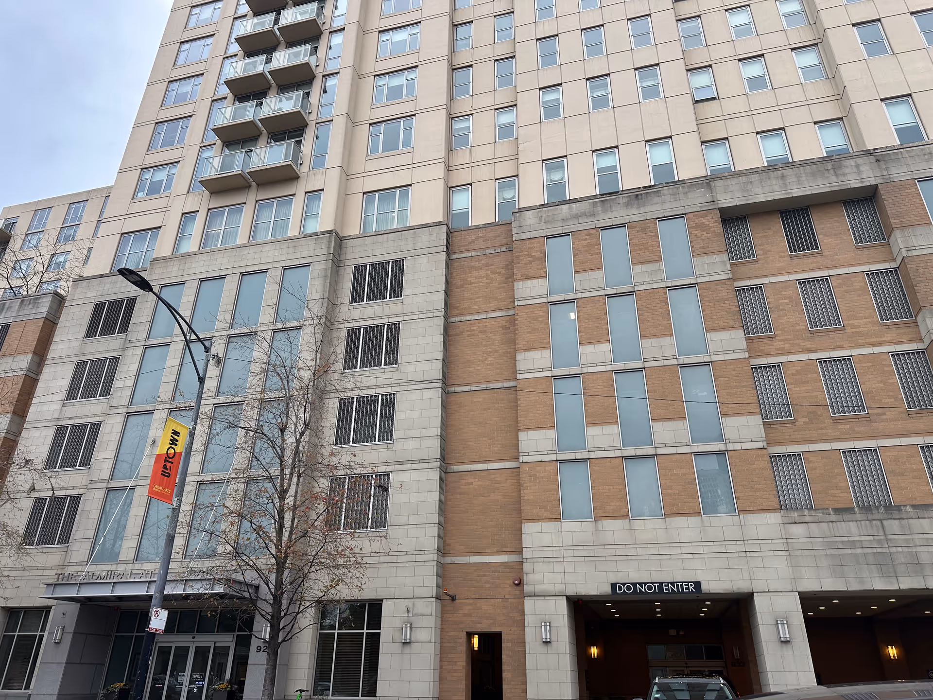 Exterior front facade of a multi-story residential building with windows, balconies and a driveway entrance marked "DO NOT ENTER".