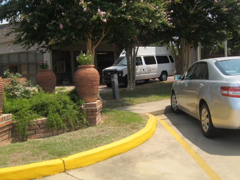 Exterior view of the Summit Retirement Center with a van and a parked car near flower pots.
