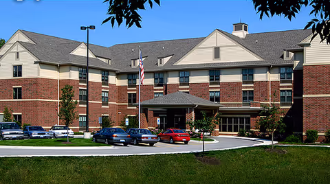 Exterior view of Victory Centre of Elk Grove Village with brick building, entrance, and parked cars.