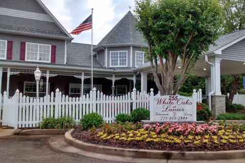 Exterior view of Country Village Senior Living with white picket fence and landscaped entrance.