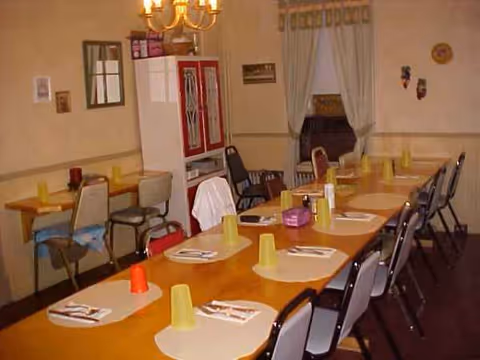 A long dining table set with yellow cups and napkins in a senior living dining room.