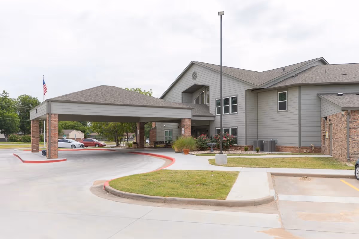 Exterior view of Hickory Crossing senior living facility with a covered entrance, parking area, and landscaping.
