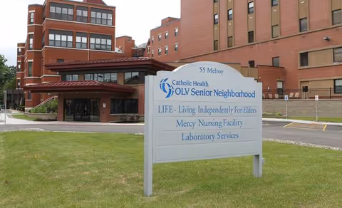 Brick building with a grassy lawn and a sign for Mercy Hospital Skilled Nursing Facility.