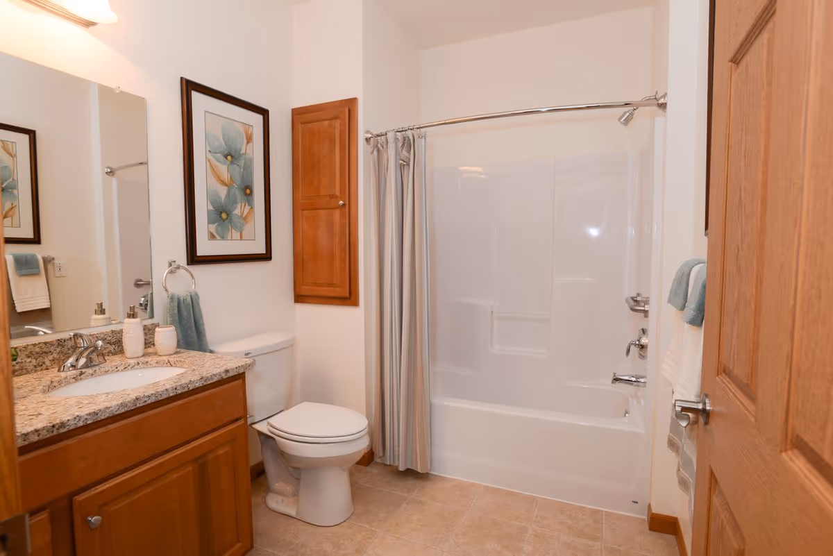 Bathroom featuring a vanity with granite countertop, toilet, and a shower-tub with a curtain.