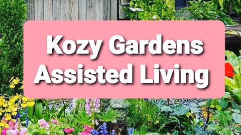 A garden area with various colorful flowers and green plants, overlaid with a pink rectangular banner displaying the text 'Kozy Gardens Assisted Living'.