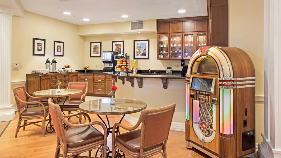 Small dining/lounge area with round tables and chairs, a service counter with a beverage station, and a vintage jukebox.