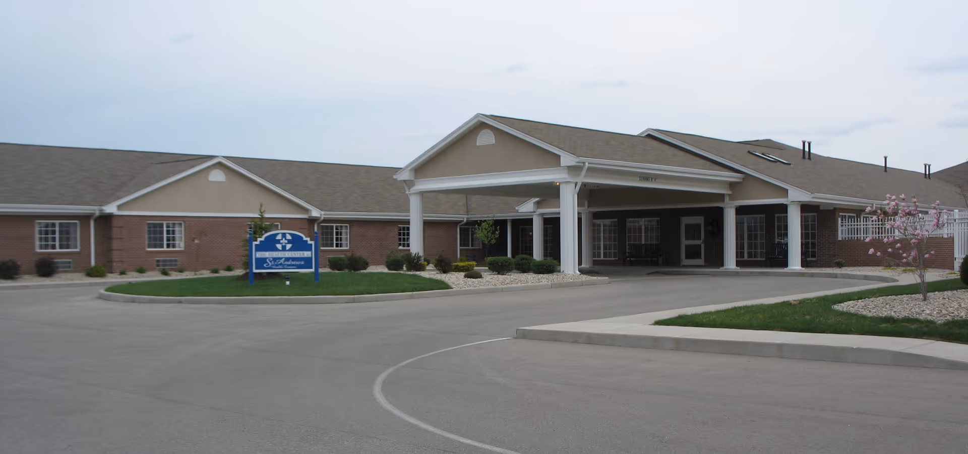 Entrance of St. Andrews Health Campus showing a single-story brick building with a covered drive-through porte-cochere and a lawn sign.