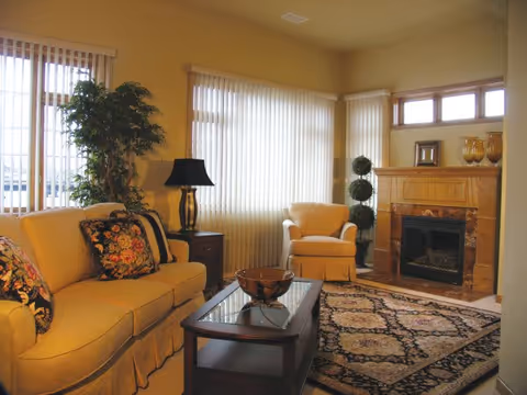 Bright, cozy living room with a sofa, armchair, coffee table, patterned rug and fireplace.