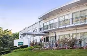 Exterior view of Twin Oaks Rehabilitation & Nursing Center with balconies, lawn, and a parked truck.