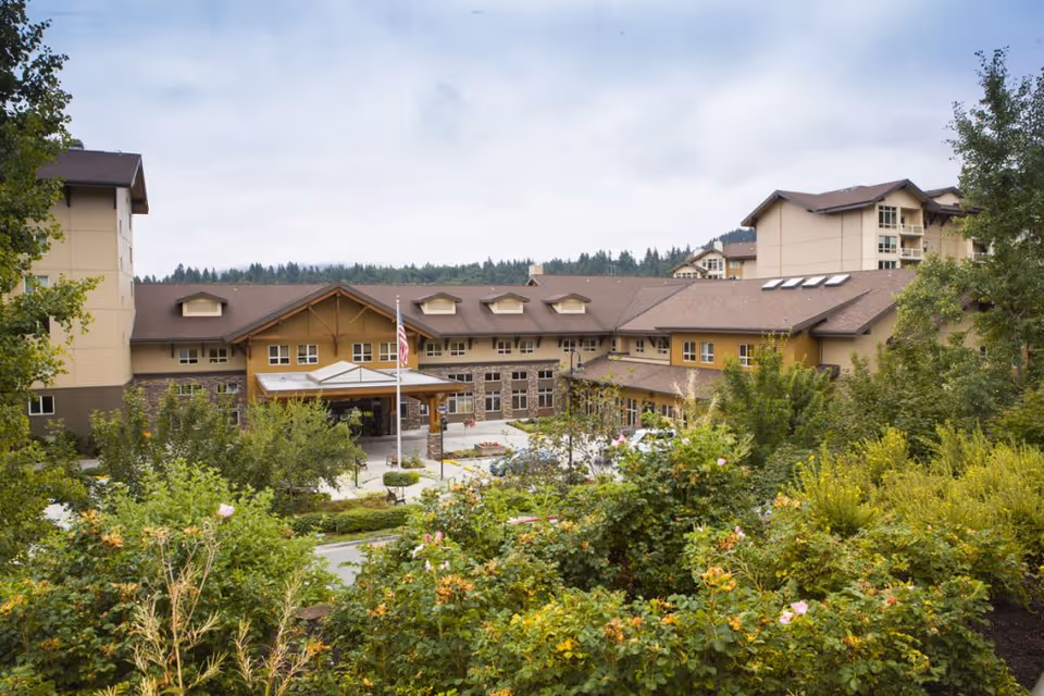 Front exterior of the Timber Ridge at Talus senior living facility with landscaped grounds and a covered entrance canopy.
