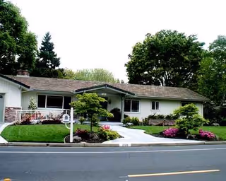 Front view of a single-story care home with manicured lawn and driveway.