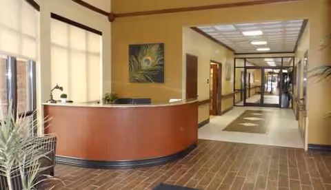 Lobby of a senior living facility with a curved reception desk and hallway.
