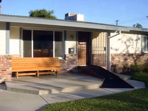 Sunny Beach Villa front entrance with bench, ramp, and brick exterior