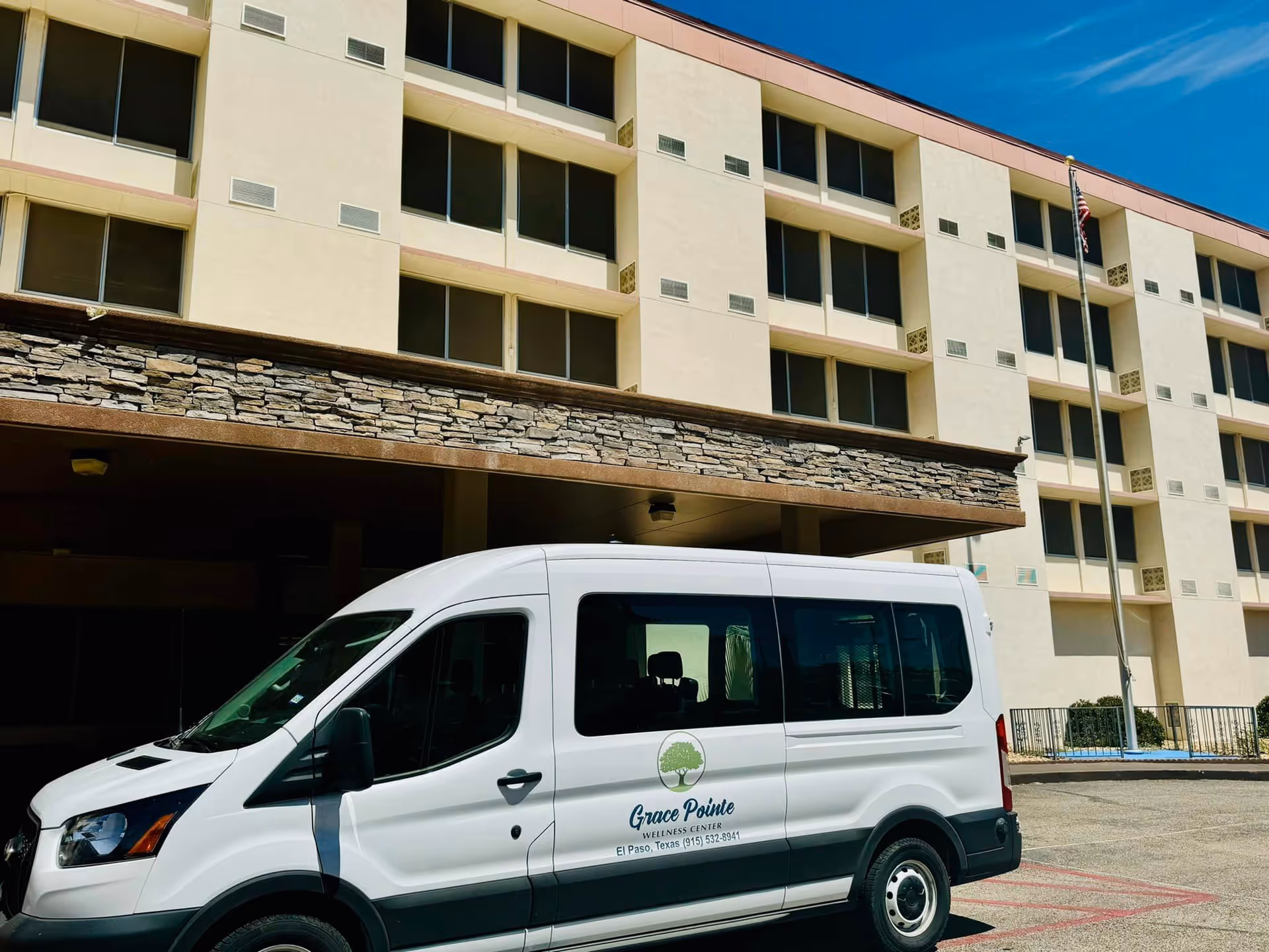 A white Grace Pointe Wellness Center shuttle van parked in front of a multi-story senior living facility building.