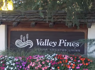 Valley Pines Senior Assisted Living entrance sign with a flowering bed in front