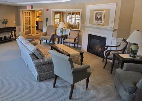 Cozy communal living room with couches, chairs, a fireplace, lamps, and tables.