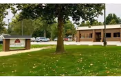 Exterior view of Keosauqua Health Care Center with lawn, trees, and a parked car