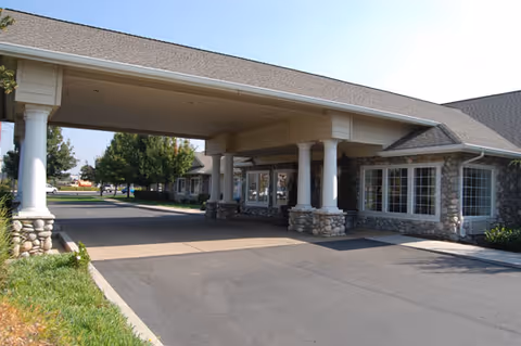 Exterior view of Brookdale Kettleman Lane showing a covered entrance with stone pillars and large windows.