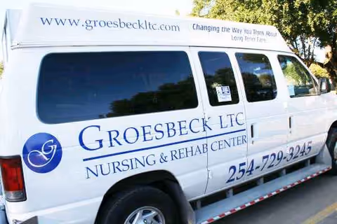 White Groesbeck LTC Nursing & Rehab Center van with blue logo parked outdoors.