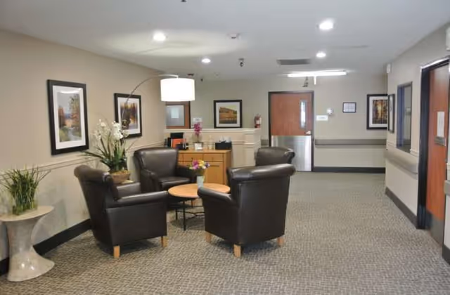 Senior living lobby with black leather chairs, round tables, plants, and a front desk