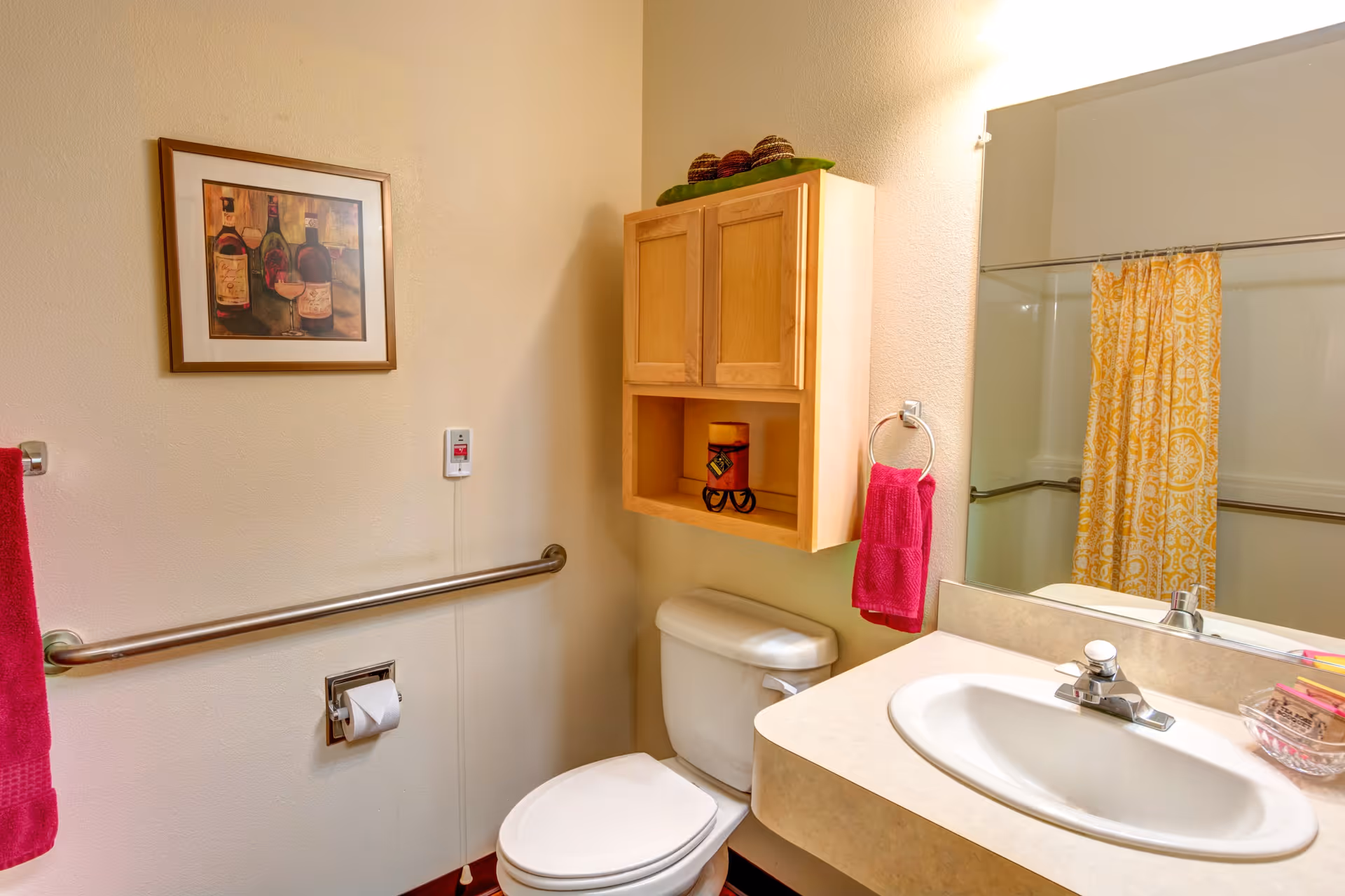Accessible bathroom with a toilet, sink and mirror, wooden wall cabinet, grab bar, and a shower with a yellow curtain.
