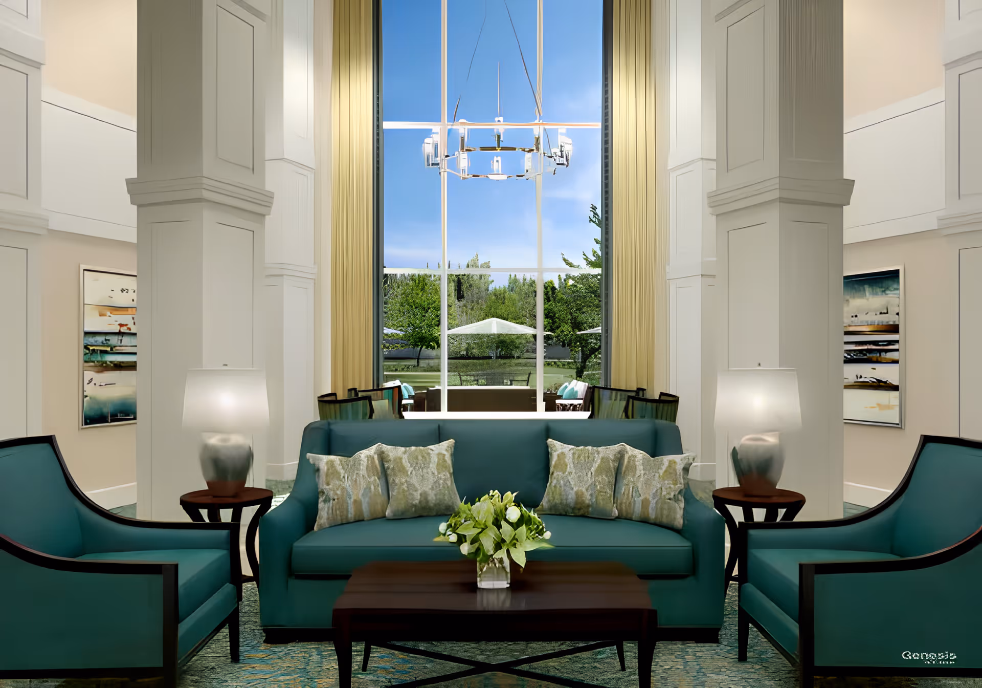 A bright and elegant living room area with teal upholstered sofa and armchairs, a wooden coffee table with a floral centerpiece, two side tables with lamps, and large windows with beige curtains offering a view of a green outdoor space with trees and a white umbrella.