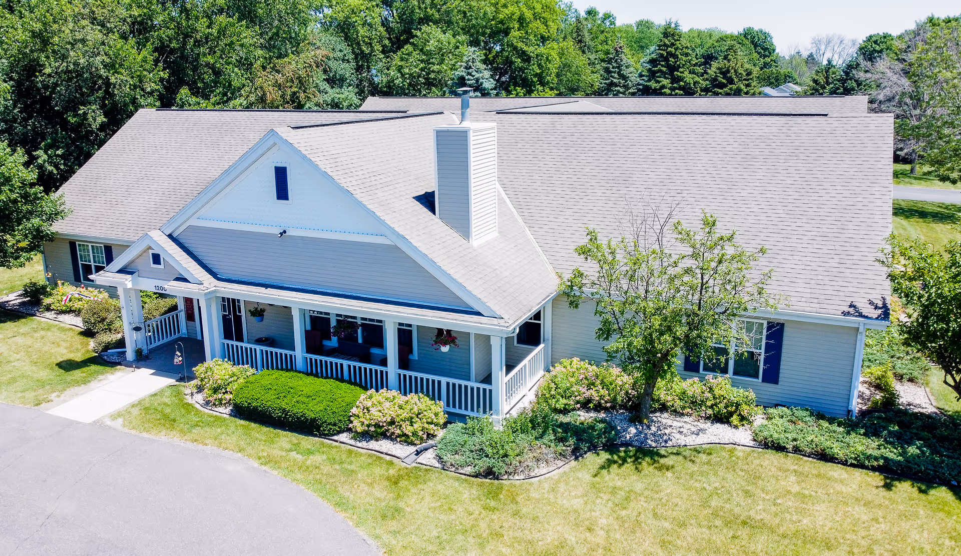 A single-story assisted living building with a covered front porch, landscaped shrubs and lawn, viewed from above.