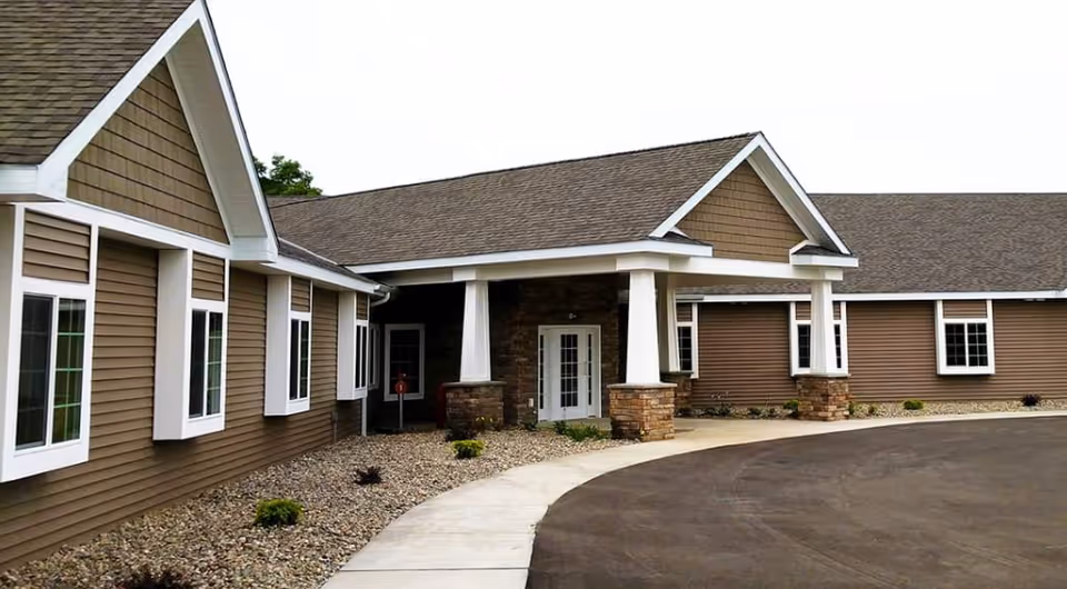 Exterior of a brown-siding assisted living building with white trim and entrance columns.