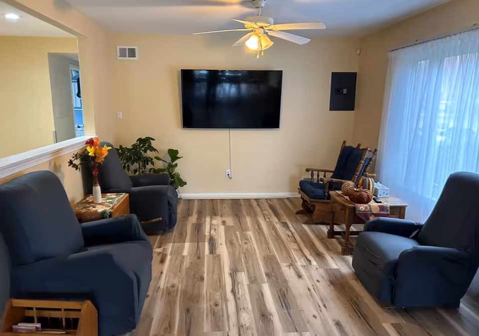 Cozy living room with blue recliners, a wall-mounted TV, and plants.