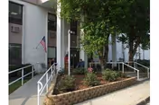 Exterior view of Falkville Rehabilitation and Healthcare Center with entrance, ramp, flag, and landscaping.