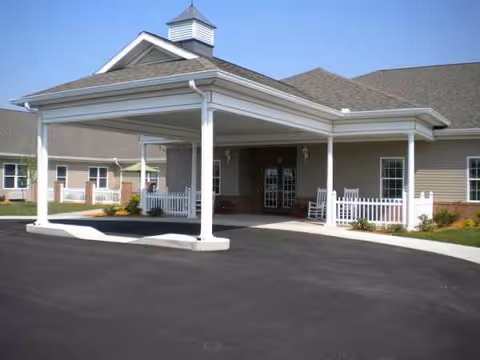 Senior living facility entrance with a covered portico and white railings.
