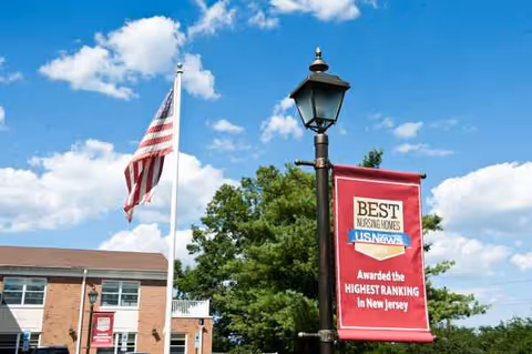 Exterior view of Emerson Health and Rehabilitation Center with flag, lamppost, and award sign.