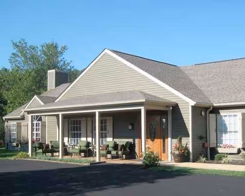 Exterior view of a single-story senior living facility with a covered front porch and seating.