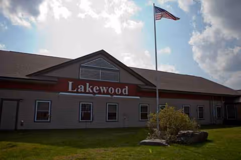 Brick exterior of Lakewood Continuing Care Center with flagpole, windows, and landscaping.