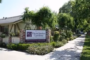 Entrance sign for Westchester Gardens by a landscaped walkway in front of a single-story building.